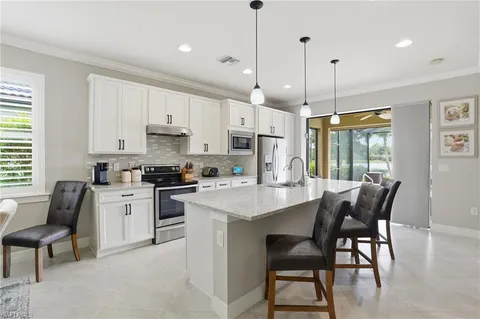 a kitchen with stainless steel appliances granite countertop a stove a sink a refrigerator a stove a dining table and chairs with wooden floor