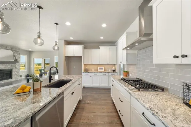 a large kitchen with stainless steel appliances granite countertop a sink a stove and a wooden floors