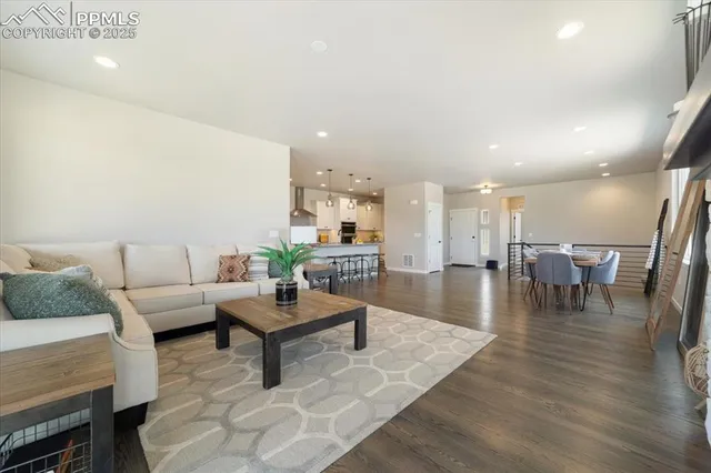 a living room with furniture and a dining table with wooden floor