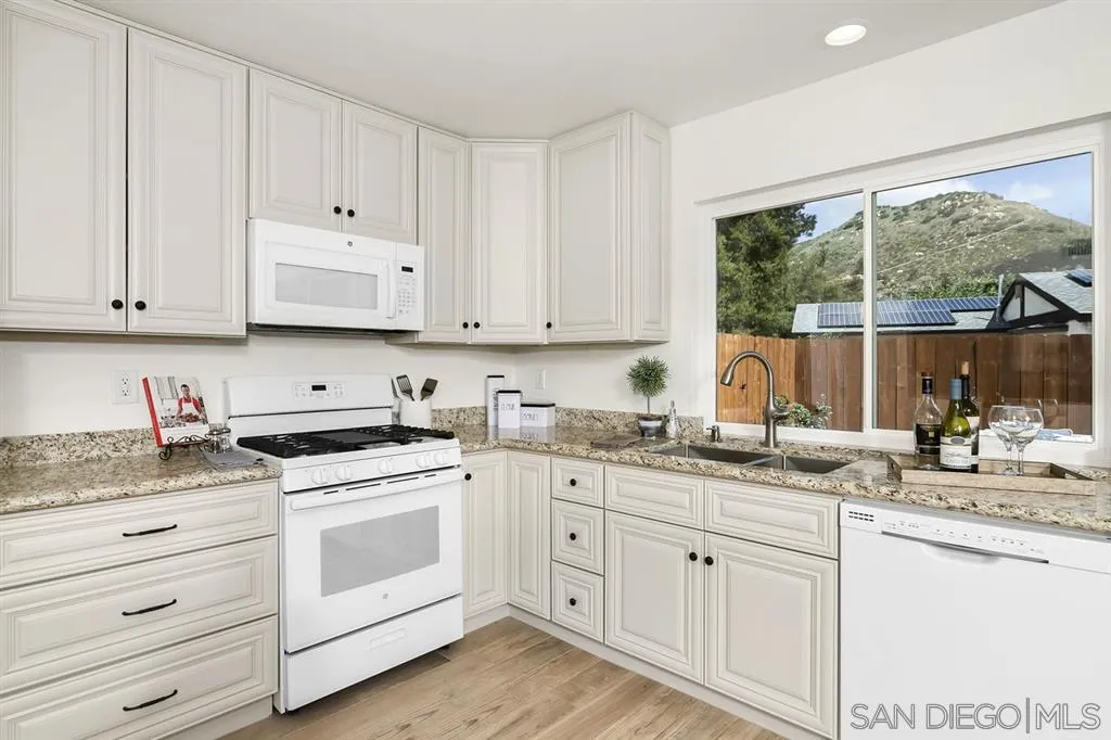 14425 Range Park Road Poway, CA 92064 - Photo 7 of 25 a kitchen with granite countertop white cabinets and white appliances