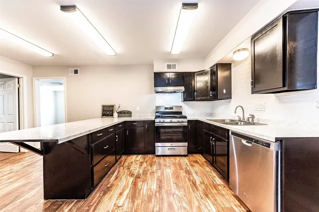 a large kitchen with granite countertop lots of counter top space and stainless steel appliances
