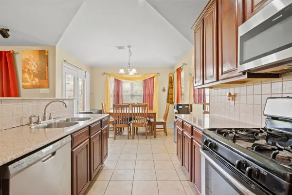 a kitchen with stainless steel appliances granite countertop a sink stove and cabinets