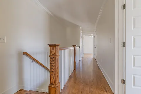 a view of a hallway with wooden floor and staircase