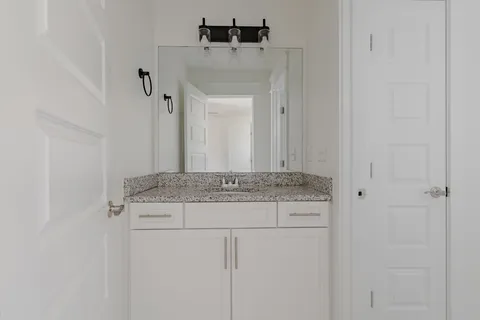 a bathroom with a granite countertop sink a toilet and a mirror