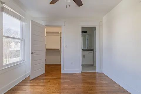 a view of empty room with wooden floor and fan