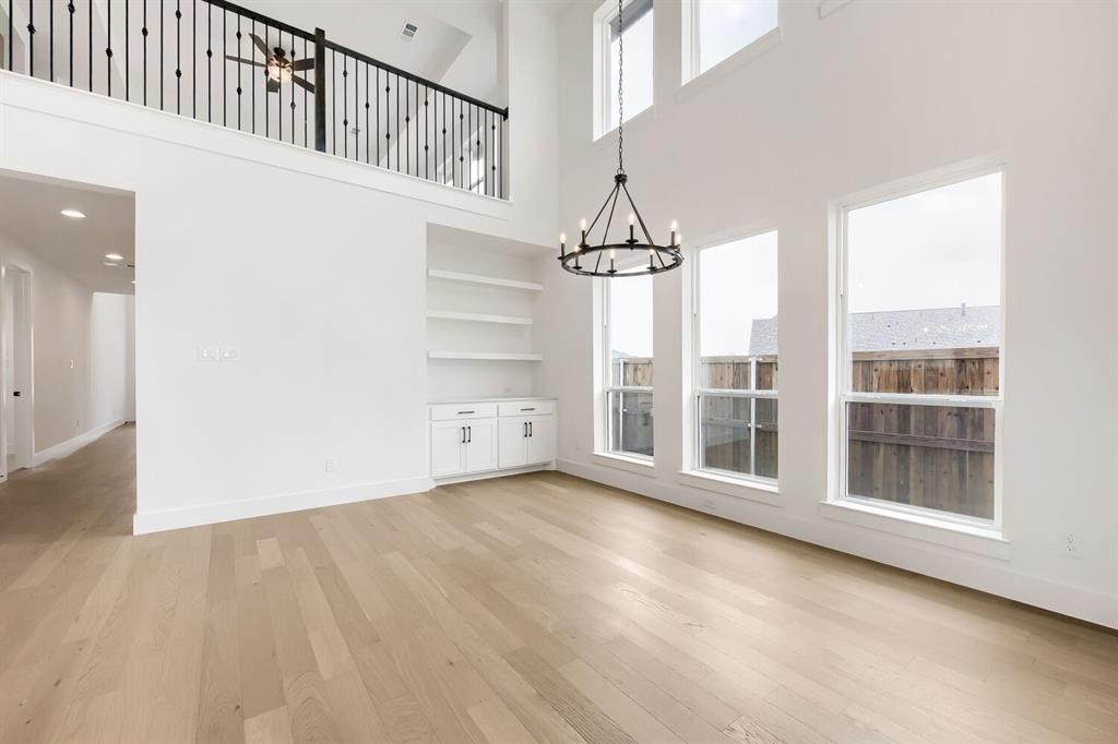 733 Red Cedar Road Haslet, TX 76052 - Photo 4 of 28 Spacious room featuring soaring ceilings, abundant natural light from multiple windows, wood-finish flooring, built-in shelving, and a decorative chandelier