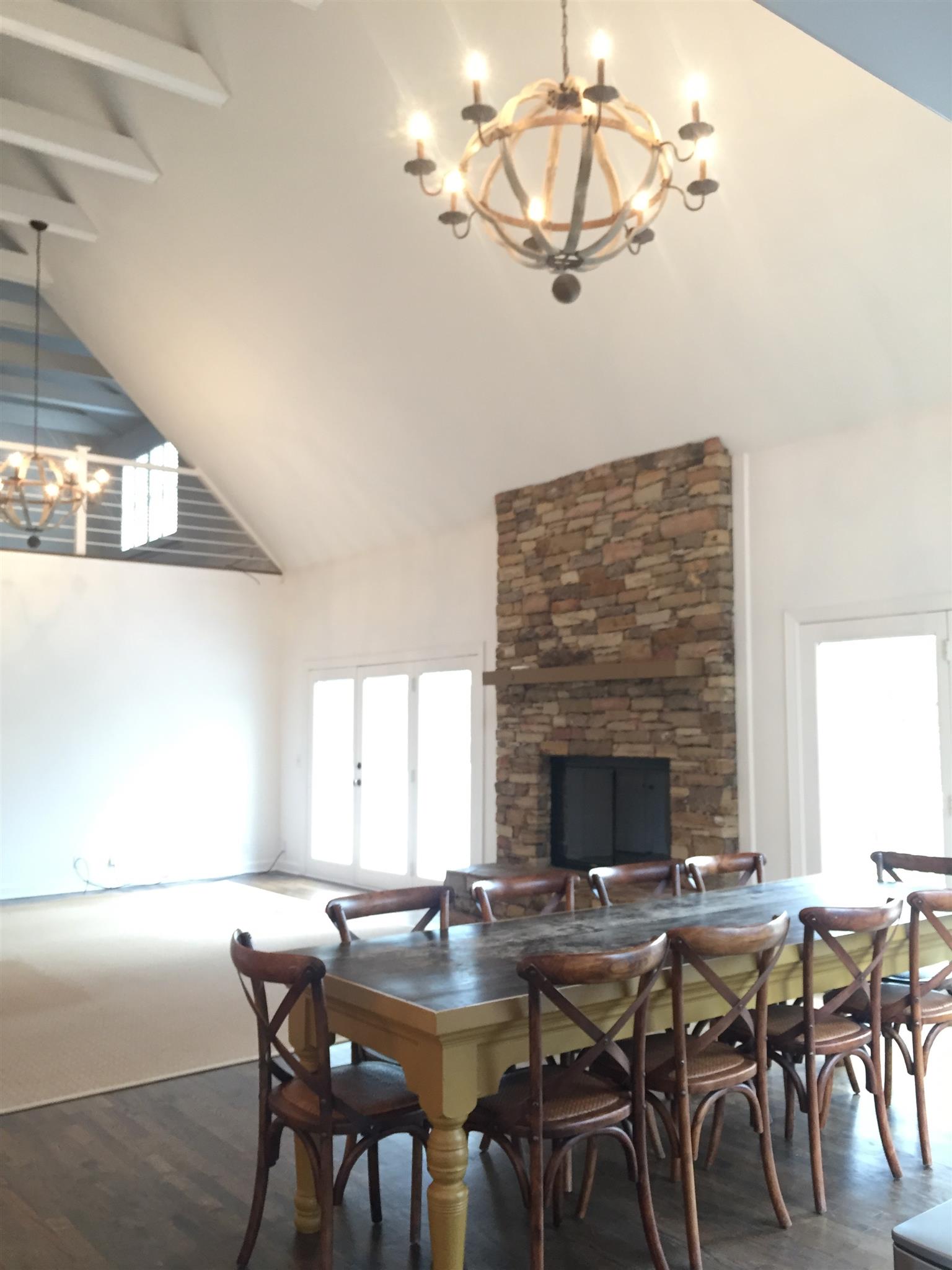 9366 Hester Beasley Road Nashville, TN 37221 - Photo 3 of 29 The Soaring Two Story Living Room Features a Brick Fireplace, Wood Beams, Designer Chandeliers, and Hardwood Floors.