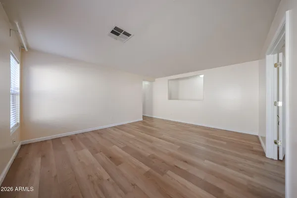 a view of an empty room with wooden floor and a window