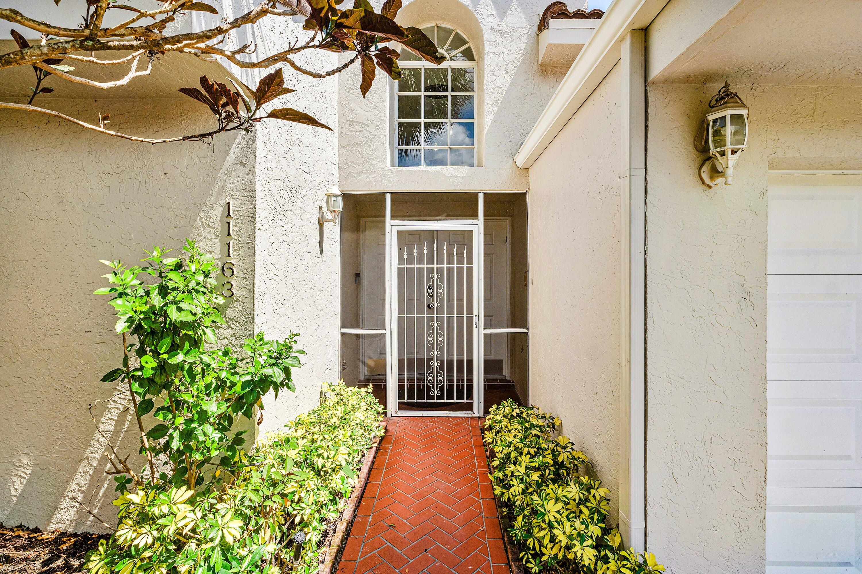 11163 180th Court South Boca Raton, FL 33498 - Photo 7 of 22 a view of a pathway of a house with potted plants