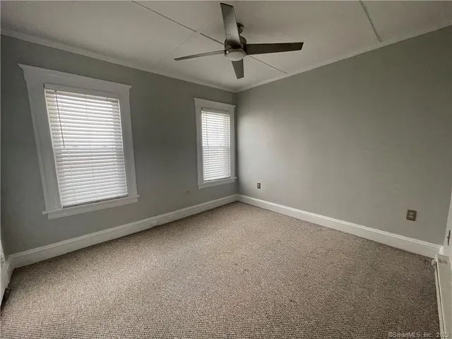 an empty room with a window and a fan