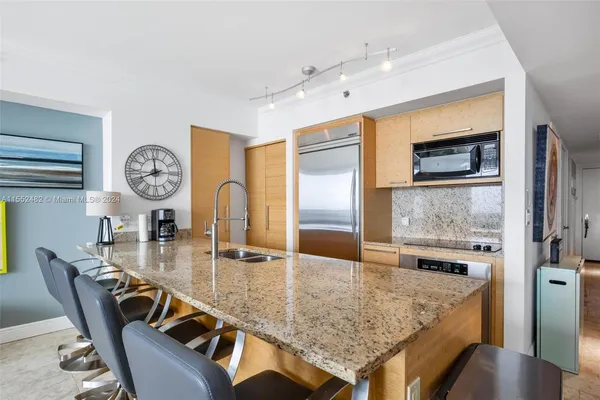 a dining hall with stainless steel appliances granite countertop a kitchen island a furniture a stove and a view of kitchen