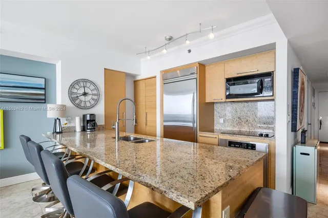 a dining hall with stainless steel appliances granite countertop a kitchen island a furniture a stove and a view of kitchen