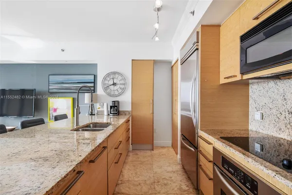 a kitchen with granite countertop a sink a stove top oven and refrigerator