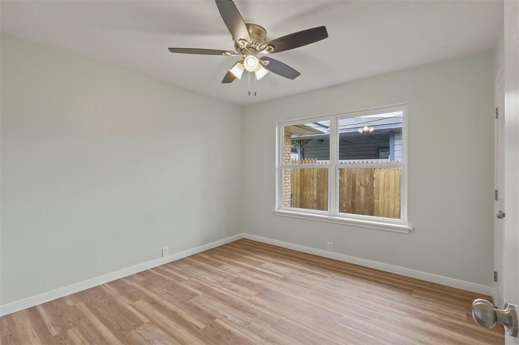 732 Bullock Street Denison, TX 75020 - Photo 11 of 29 an empty room with wooden floor fan and windows
