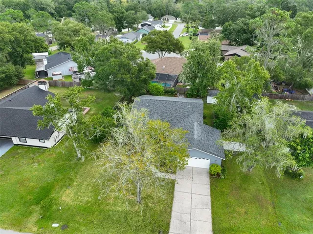 an aerial view of residential house with outdoor space and trees all around