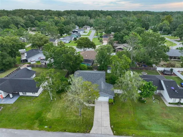 an aerial view of residential houses with outdoor space and trees