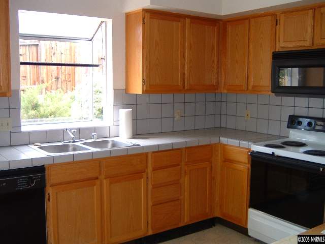 6052 Walnut Creek Road Reno, NV 89523 - Photo 3 of 5 a kitchen with stainless steel appliances granite countertop wooden cabinets a sink and a window