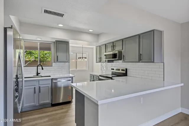 a large white kitchen with kitchen island a sink and a large window