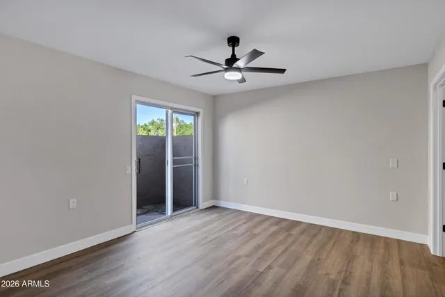 a view of empty room with wooden floor and ceiling fan