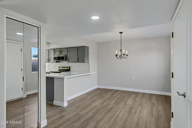 a view of an empty room with wooden floor and a mirror