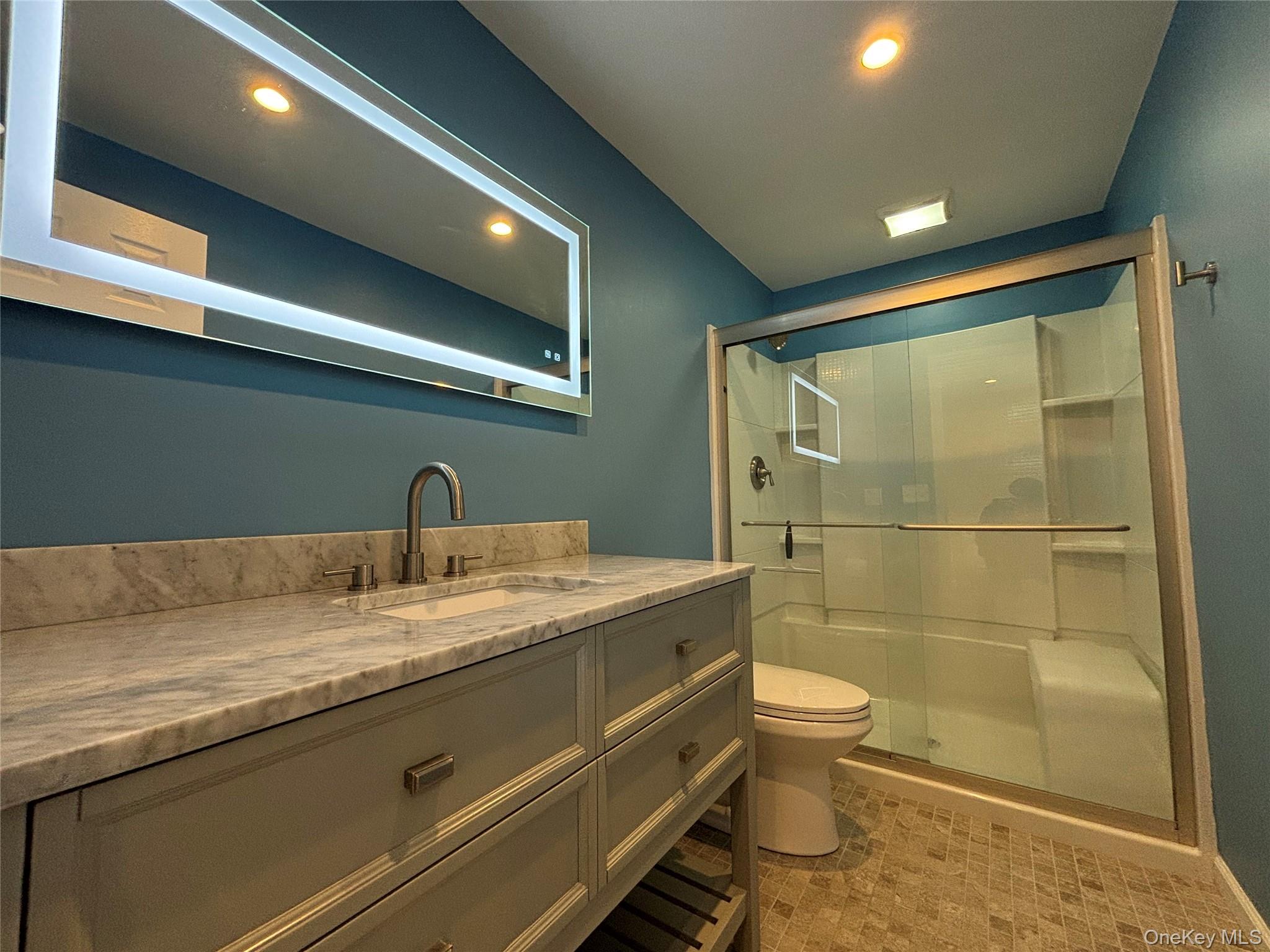 45 Waterstone Road, Unit 2 Greenwood Lake, NY 10925 - Photo 9 of 10 a bathroom with a granite countertop sink a toilet a mirror and shower