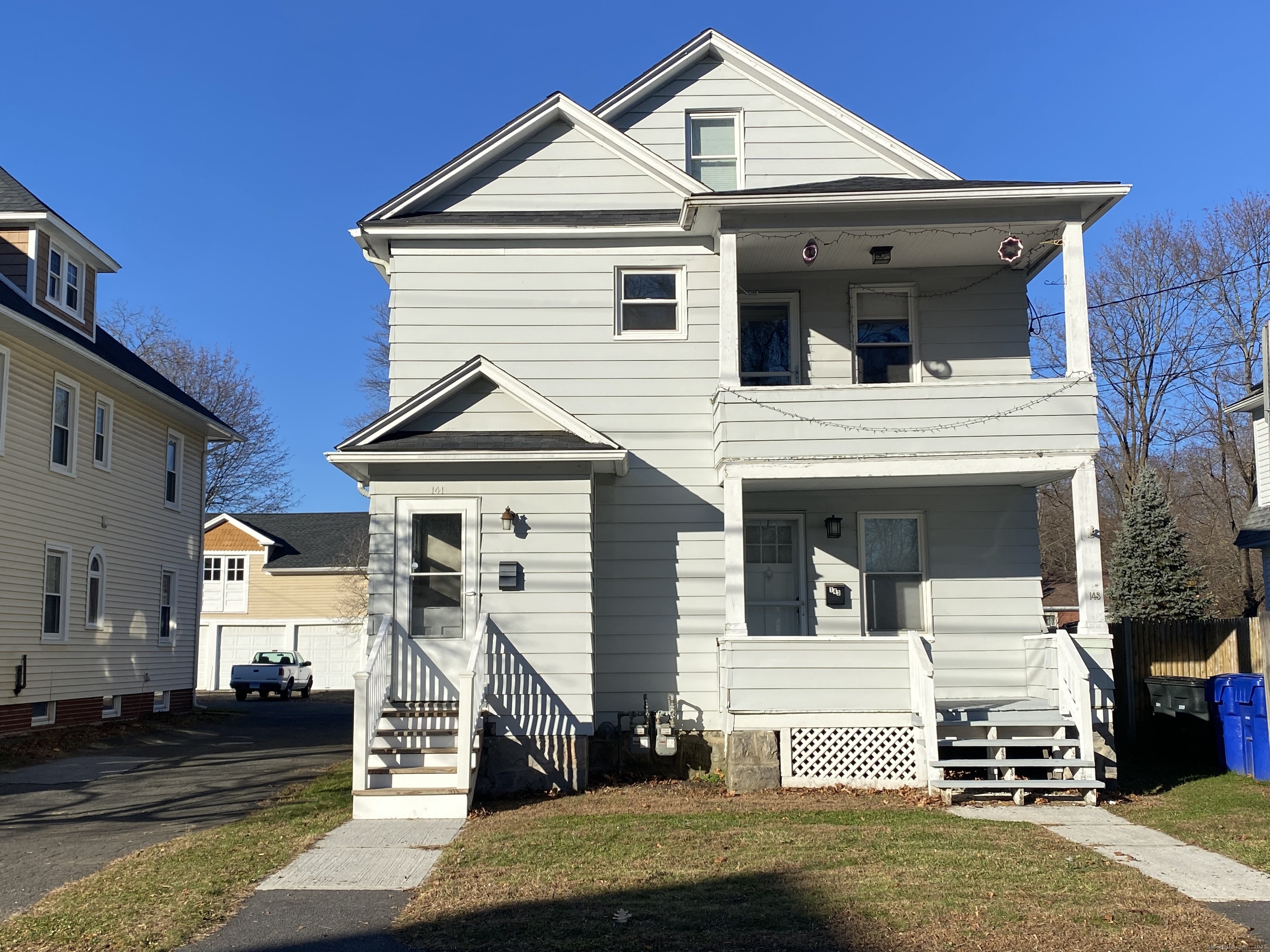 a view of a white house with a small yard and large tree
