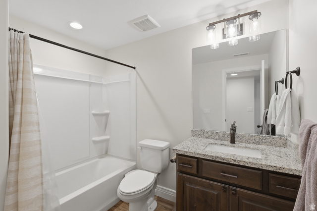 10676 Urban Rdg Cove South Jordan, UT 84095 - Photo 20 of 48 Bathroom featuring a tub/shower combination with white surround, a dark wood-finish vanity with a light-toned speckled countertop and undermount sink, a bronze-finish faucet, and coordinating bronze-finish light fixture