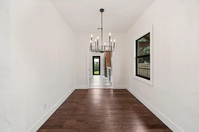 a view of a hallway with wooden floor and a chandelier