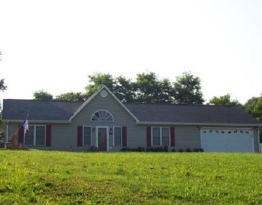a front view of house with yard and trees in the background