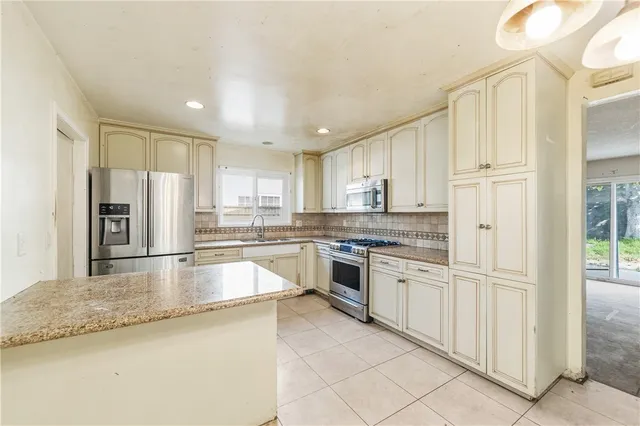 a kitchen with stainless steel appliances granite countertop a refrigerator and a stove top oven