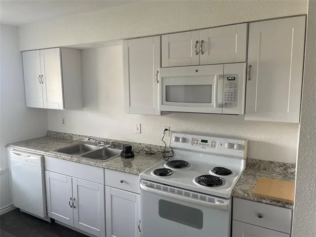 a kitchen with white cabinets and white appliances