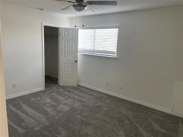 an empty room with a window and a ceiling fan