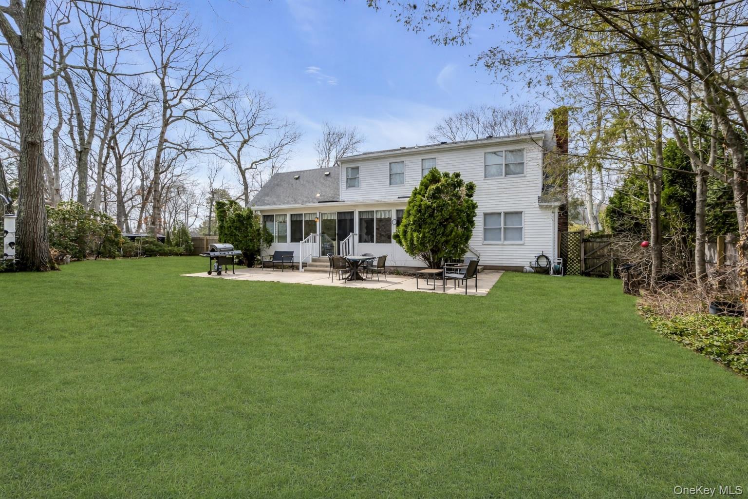 5845 North Bayview Road Southold, NY 11971 - Photo 23 of 26 Back of structure featuring a yard with mature landscaping, a 4 season sunroom and patio perfect for entertaining.