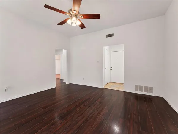 an empty room with wooden floor ceiling fan and window