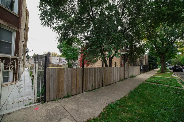 a view of a park with large trees and a wooden fence