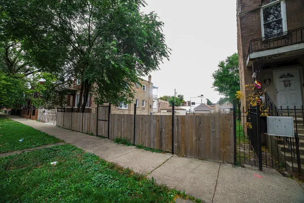 a view of a backyard with wooden fence and large trees