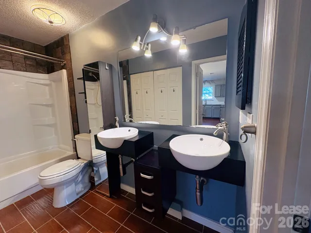 a bathroom with a sink a toilet a mirror and shower