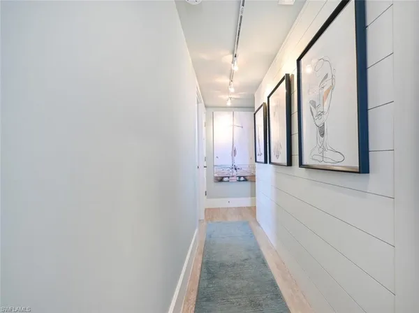 a hallway with wooden floor chandelier and livingroom