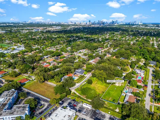an aerial view of residential houses with outdoor space and trees