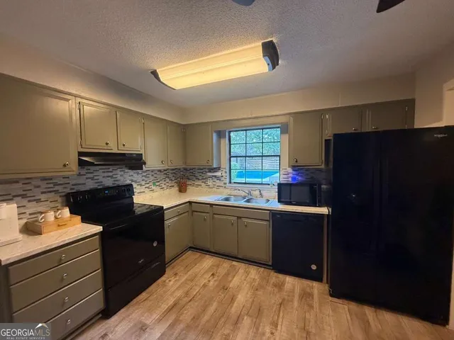 a kitchen with granite countertop a refrigerator and a stove top oven