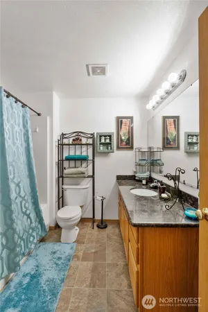 a bathroom with a granite countertop sink a toilet a mirror and shower