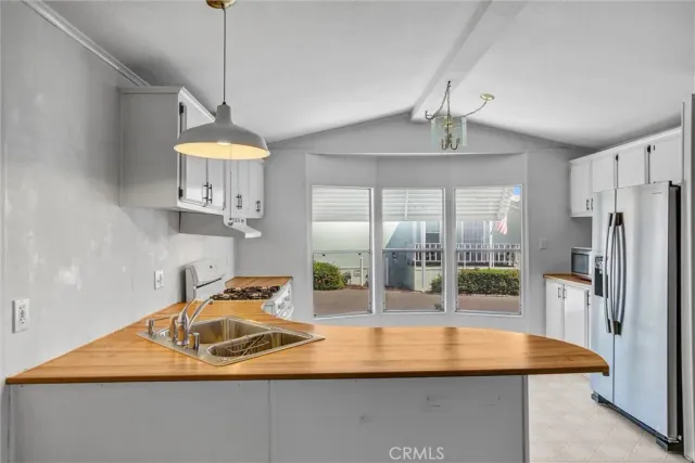 a kitchen with stainless steel appliances granite countertop a sink a refrigerator and a granite counter top