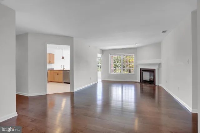 a view of an empty room with window and wooden floor