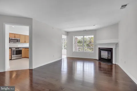 an empty room with wooden floor fireplace and windows