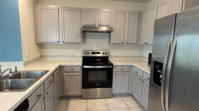 a kitchen with stainless steel appliances granite countertop a refrigerator a stove and a sink