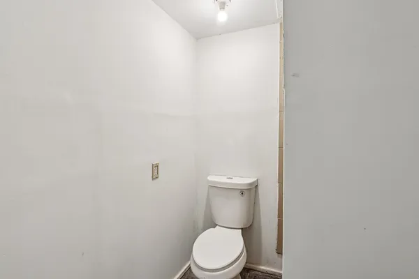a white toilet sitting next to a white wall