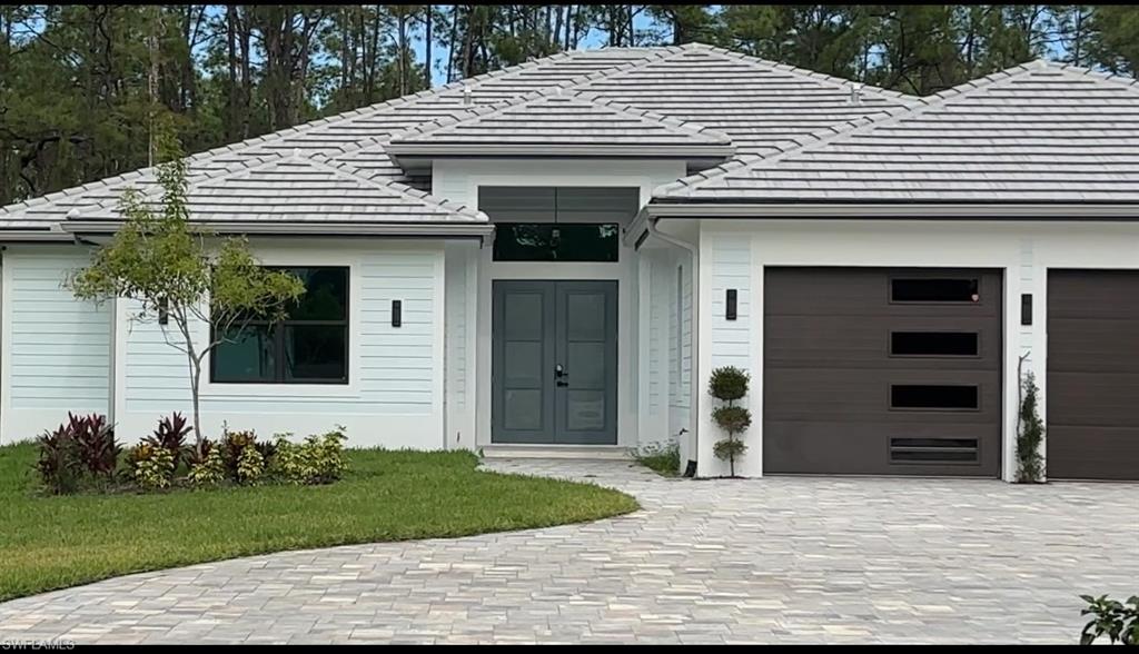 Undisclosed Address Naples, FL 34117 - Photo 2 of 23 a front view of a house with a yard and garage