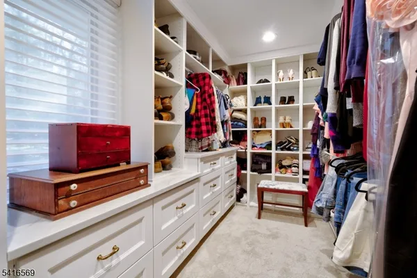 a view of walk in closet with clothes and shoes
