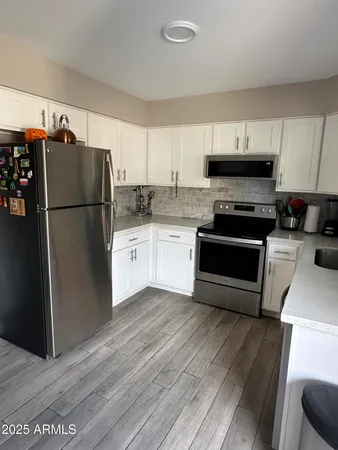 a kitchen with granite countertop a refrigerator stove a sink and dishwasher with wooden floor