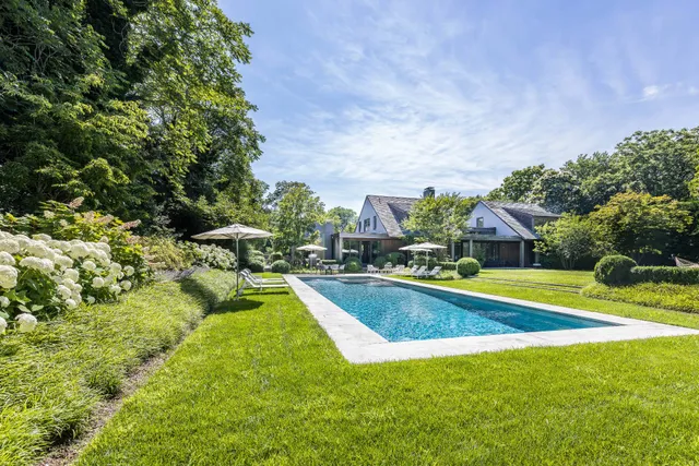 a view of swimming pool with lawn chairs and plants